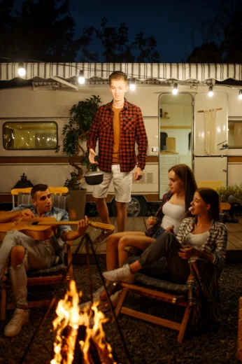 Camper am Lagerfeuer vor einem Wohnwagen